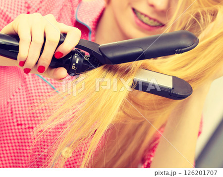 Woman wearing pajamas curling her hair Woman wearing pajamas curling her hair 126201707