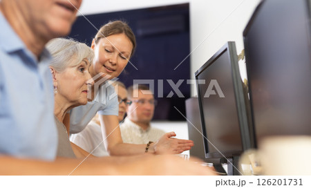 Mature people listen attentively to female teacher during computer teaching lesson in nursing home Mature people listen attentively to female teacher during computer teaching lesson in nursing home 126201731