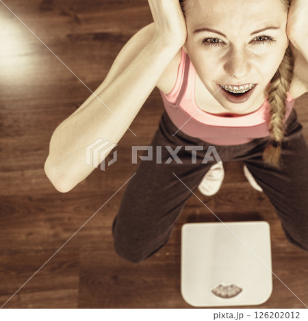 Scared woman on bathroom scale machine 126202012