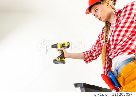 Woman using drill on ladder 126202057