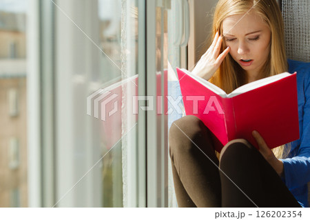 Woman reading on windowsill Woman reading on windowsill 126202354