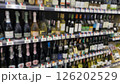 rows of wine bottles on shelves, blurred image of wine bottled on the shelf in supermarket. grocery store display wine and liquor defocus, no people. 126202529