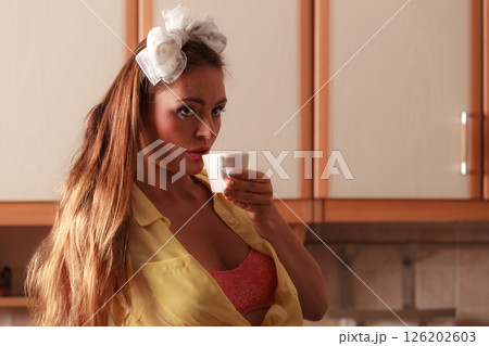 Pensive pin up girl drinking tea or coffee at home 126202603
