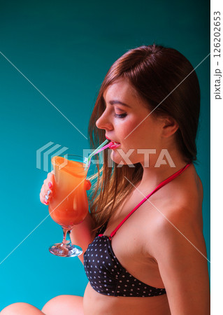 Woman with cocktail drink at swimming pool edge. 126202653