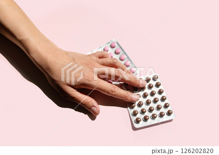 Woman Hand Reaching for Blister Package of Dietary Supplement Pills. Diet and Personal Medication Management Plan. Woman Hand Reaching for Blister Package of Dietary Supplement Pills. Diet and Personal Medication Management Plan. 126202820