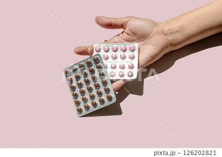 Woman Holding Two Packs of Dietary Supplements or Pills. Options for Nutrition and Wellness, with Daily Dosage Concept. Woman Holding Two Packs of Dietary Supplements or Pills. Options for Nutrition and Wellness, with Daily Dosage Concept. 126202821