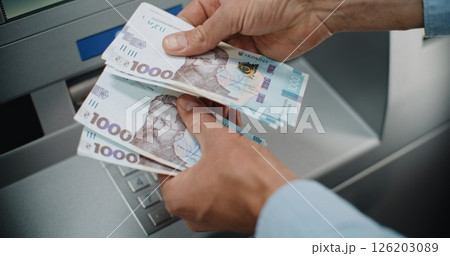 Close Up of Man Counting Hryvnia Bills After Withdrawing Cash Money from ATM Machine Close Up of Man Counting Hryvnia Bills After Withdrawing Cash Money from ATM Machine 126203089