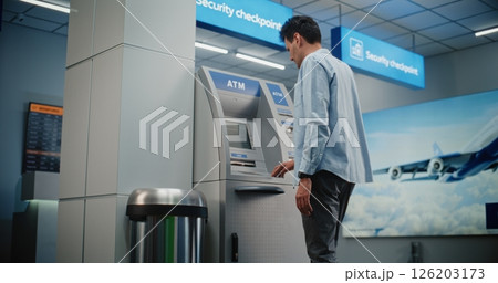 ATM Machine in Airport Terminal: Man Entering PIN Code for Money Withdrawal Operation, Taking Cash 126203173