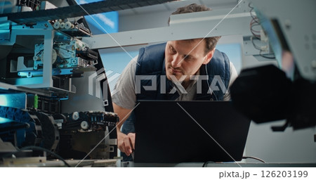 Technician Analyzing Internal Components of ATM Machine Using Laptop 126203199