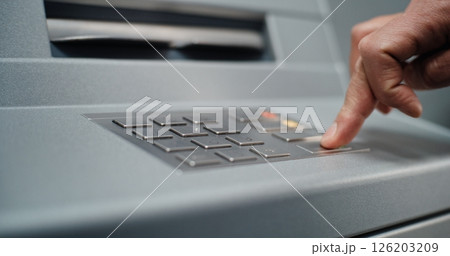 ATM Machine: Close Up of Unrecognizable Man Entering PIN Code for Cash Withdrawal Transaction ATM Machine: Close Up of Unrecognizable Man Entering PIN Code for Cash Withdrawal Transaction 126203209