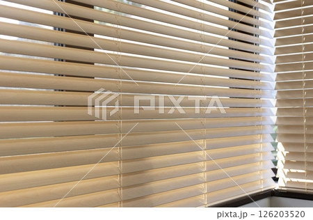 Light filtering through wooden blinds in cozy indoor space during daylight hours 126203520