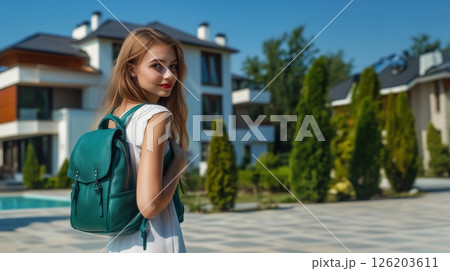 Girl with emerald leather backpack stands in modern neighborhood enjoying clear day with stylish contemporary homes in view 126203611