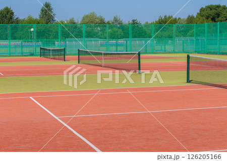 The tennis court is empty with a net and a green fence. 126205166