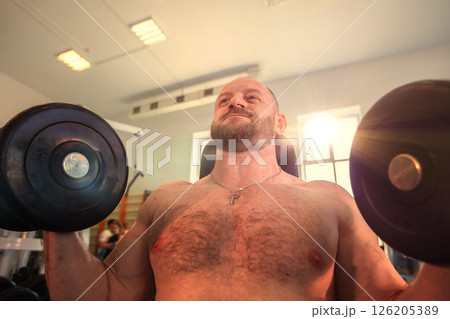 Bearded man lifting weights in the gym. Concept of strength and determination 126205389
