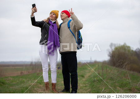Active elderly Caucasian couple traveling with backpacks, enjoying their adventure. They take selfies. Active elderly Caucasian couple traveling with backpacks, enjoying their adventure. They take selfies. 126206000
