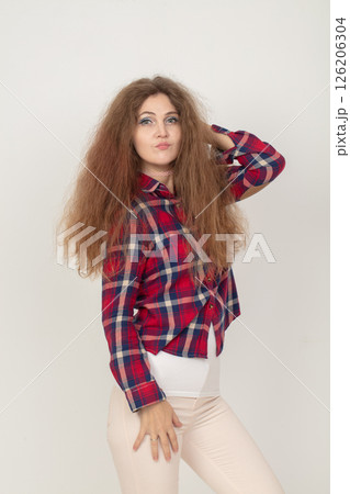 A woman with long hair is wearing a red and white plaid shirt. She is posing for a picture and has her hand on her chin A woman with long hair is wearing a red and white plaid shirt. She is posing for a picture and has her hand on her chin 126206304