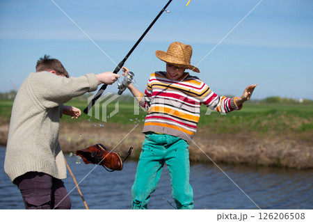 Funny fishing. Two of the boy's friends hooked an old shoe with a fishing rod and are laughing. 126206508