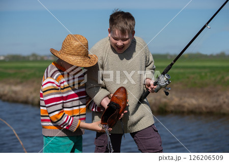 Funny fishing. Two of the boy's friends hooked an old shoe with a fishing rod and are laughing. 126206509