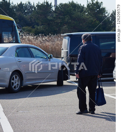 観光地の駐車場の車に向かうシニア男性の姿 126206579