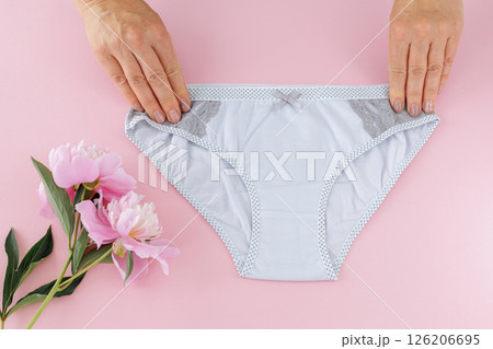 Women's hands with a gray panties on the pink background. 126206695