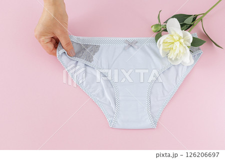 Woman's hand with a gray panties on the pink background. 126206697
