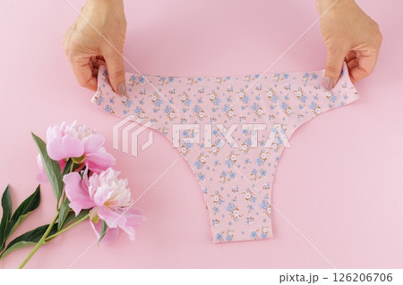 Women's hands with a pink panties on the pink background. Women's hands with a pink panties on the pink background. 126206706
