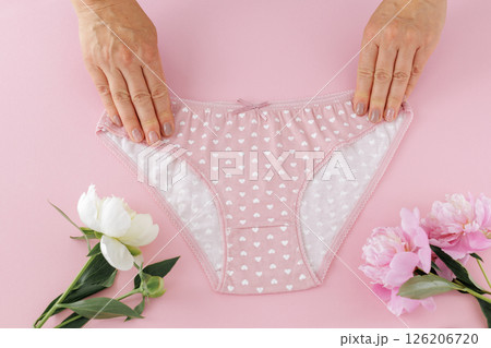 Women's hands with a pink panties on the pink background. Women's hands with a pink panties on the pink background. 126206720