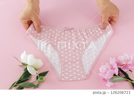Women's hands with a pink panties on the pink background. 126206721