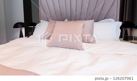 Close-up of a cozy modern hotel bed with soft pastel pillows and elegant bedding in a relaxing interior 126207061