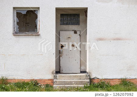 Abandoned building detail with damaged doors and broken glass on window 126207092