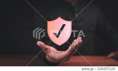 Male hand showing a glowing shield with the checkmark icon, symbolizing security, protection, and trust. Concept of emphasizes digital safety, authentication, and confidence in modern technology. 126207120