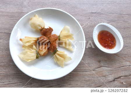golden bag crispy fried dumpling paste stuffed chop pork and shrimp Thai snack dipping sweet chili plum sauce on cup 126207282
