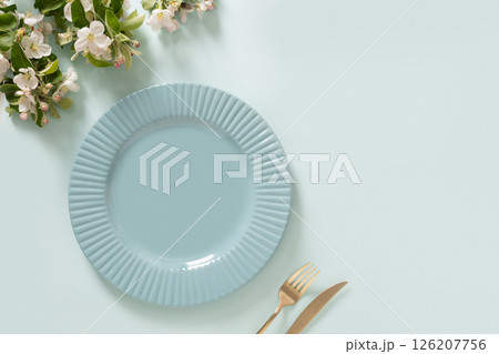 Elegance empty blue plate and spring blossom flowers on blue background. Mock up. Table setting concept. Kitchen decoration, food styling, or dining presentations. Copy space. View from above. 126207756