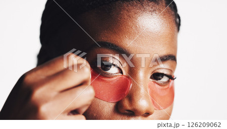 Black woman, portrait and eye patches with cosmetics for collagen or hydration on a white studio background. Face, female person or model with facial gel mask for dermatology or anti aging treatment Black woman, portrait and eye patches with cosmetics for collagen or hydration on a white studio background. Face, female person or model with facial gel mask for dermatology or anti aging treatment 126209062
