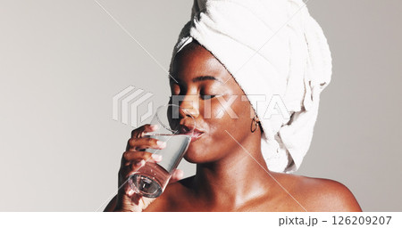 Woman, drinking water and towel for skincare in studio with diet, detox and self care by background. African girl, model and glass with liquid for gut health, wellness and beauty with hydration Woman, drinking water and towel for skincare in studio with diet, detox and self care by background. African girl, model and glass with liquid for gut health, wellness and beauty with hydration 126209207