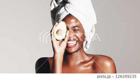 Skincare, avocado and laugh with black woman in studio for natural cosmetics, beauty and funny. Omega 3 oil, antioxidants and self care with person on white background for hydration and happiness 126209235