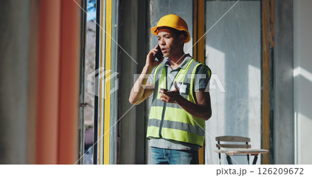 Man, phone call and talk at construction site for renovation by window, insight or negotiation for material price. Person, architecture and smartphone for discussion, property or development project 126209672