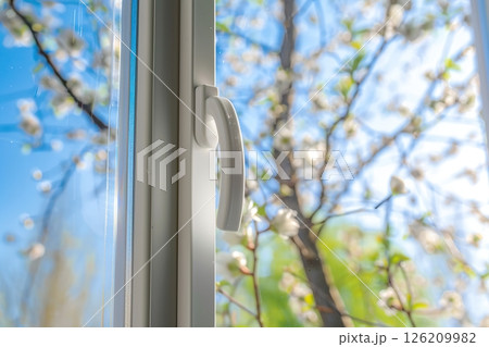 New plastic PVC window with white metal frame installed at modern house, view of blurred green trees, blue sky. Advertising. Typical installation of insulated glazing windows with uPVC window frames. 126209982