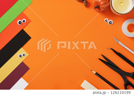 Supplies for paper crafts in Halloween colors. Pencil, eraser, knife, scissors, tape and colored pieces of paper. Copyspace. 126210199