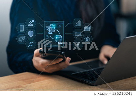 A person engages with a smartphone and a laptop, displaying AI technology and data visualization. The scene represents modern workspace innovation and digital communication. A person engages with a smartphone and a laptop, displaying AI technology and data visualization. The scene represents modern workspace innovation and digital communication. 126210245