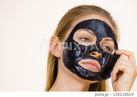 Girl removes black mask from face Girl removes black mask from face 126210829