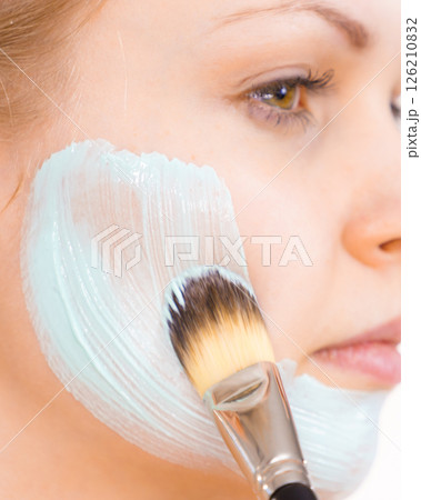 Girl apply green mud mask to face 126210832