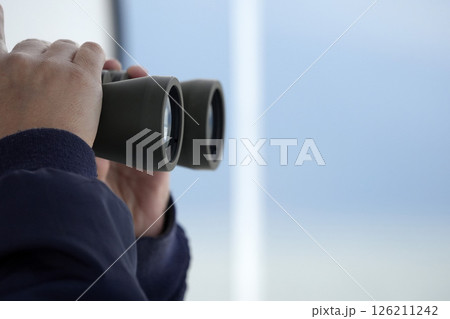 Detail of hands holding binoculars while looking and searching for wildlife on a whale watching excursion 126211242