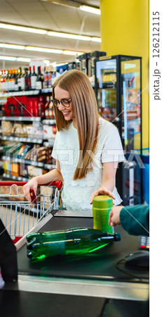 Smiling woman at checkout in vibrant grocery store environment Smiling woman at checkout in vibrant grocery store environment 126212115
