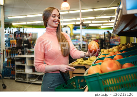 Woman enjoys selecting fresh apples in vibrant grocery store Woman enjoys selecting fresh apples in vibrant grocery store 126212120