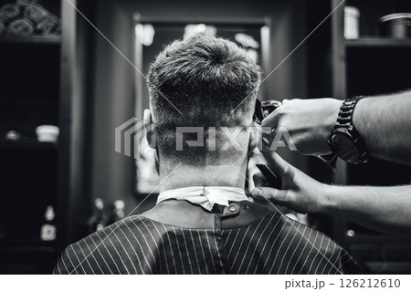 A man is getting his hair cut by a barber 126212610