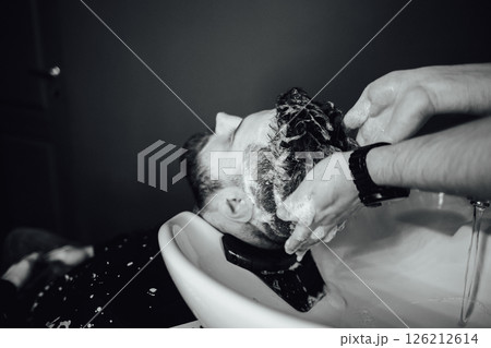 A man is getting his hair washed in a sink 126212614