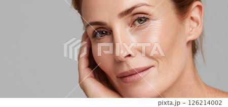 Closeup of rejuvenated face with smooth skin and natural makeup showing confidence and calmness in neutral background 126214002