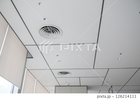 Clean modern office ceiling featuring air vents, recessed lighting, and grid pattern that creates bright and organized atmosphere. design is simple and functional 126214111