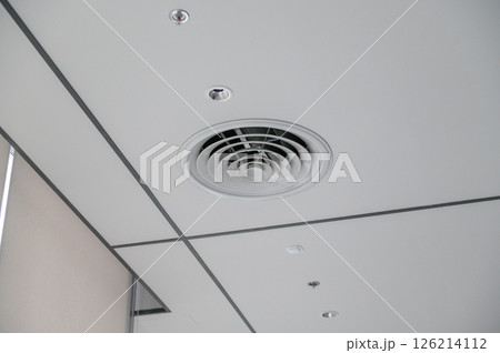 Clean modern office ceiling featuring air vents, recessed lighting, and grid pattern that creates sleek and functional workspace atmosphere 126214112